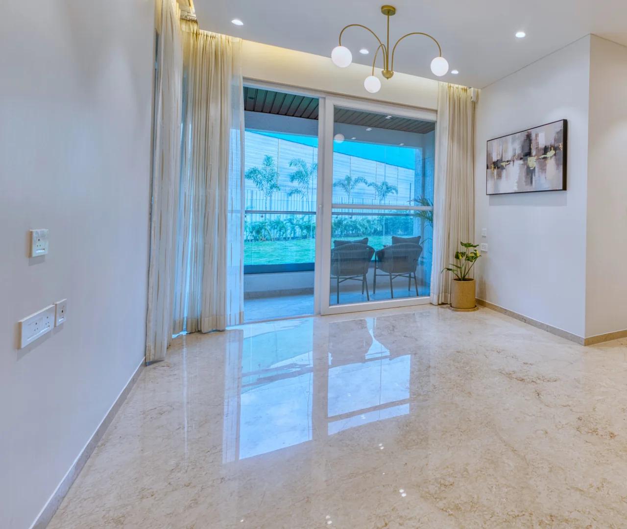 Sample flat living room with marble flooring and a sliding door to the balcony at Palladio Presidential Towers, Hadapsar